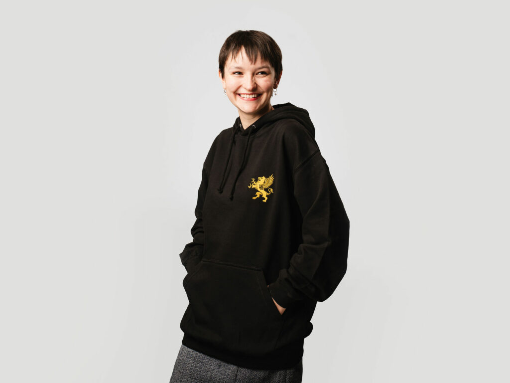 Female model wearing black hoodie with gold logo