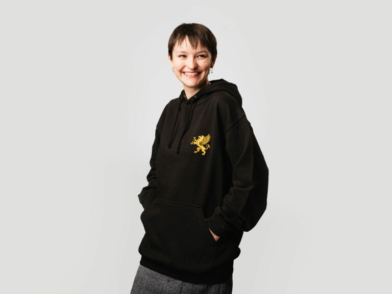 Female model wearing black hoodie with gold logo
