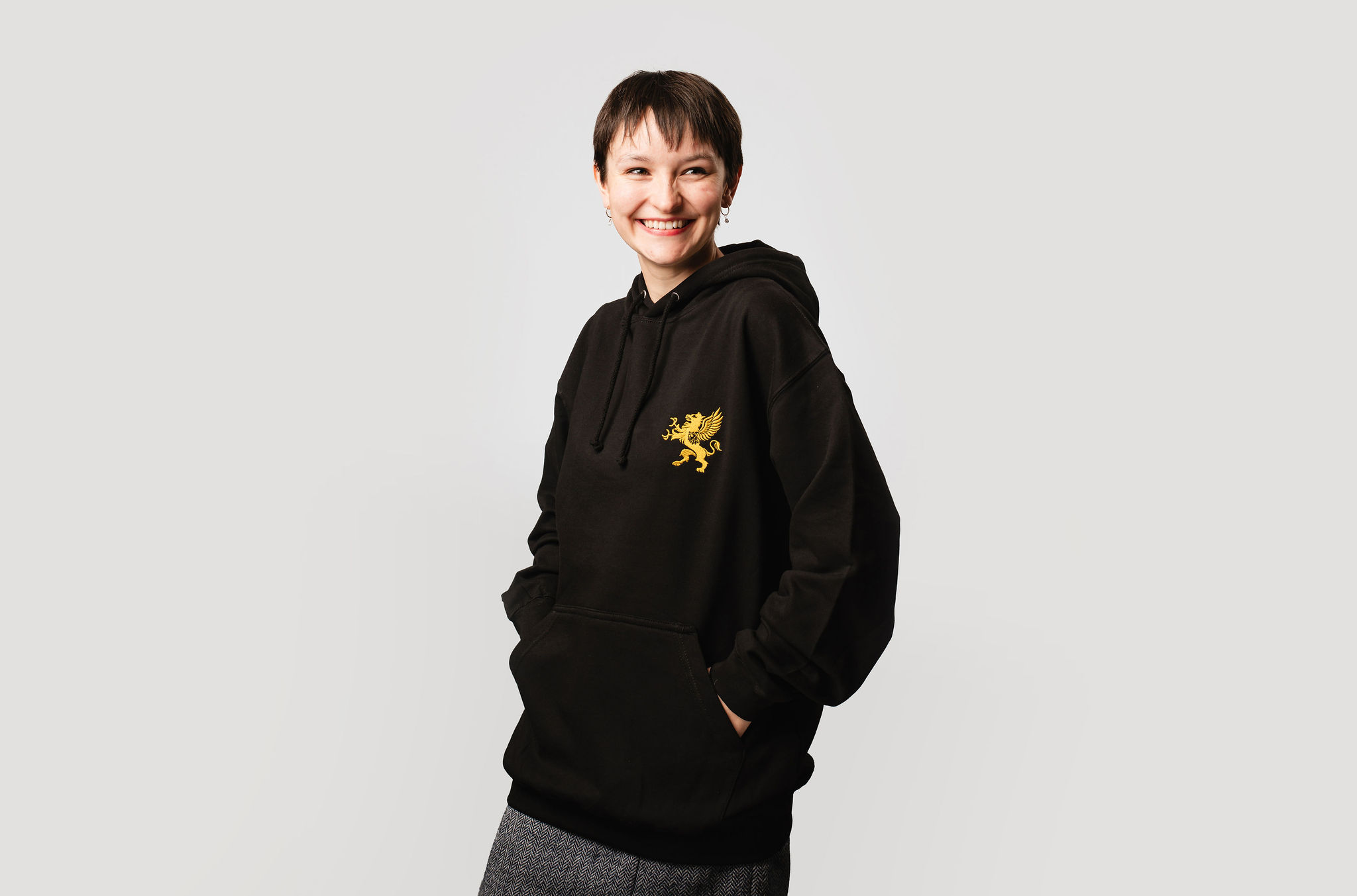 Female model wearing black hoodie with gold logo