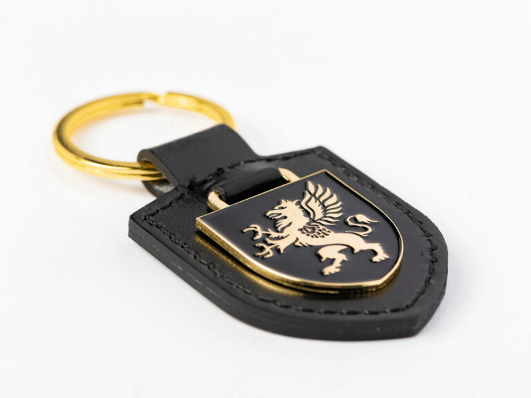 Shield keyring in black faux leather with gold enamel griffin laid flat on a white background