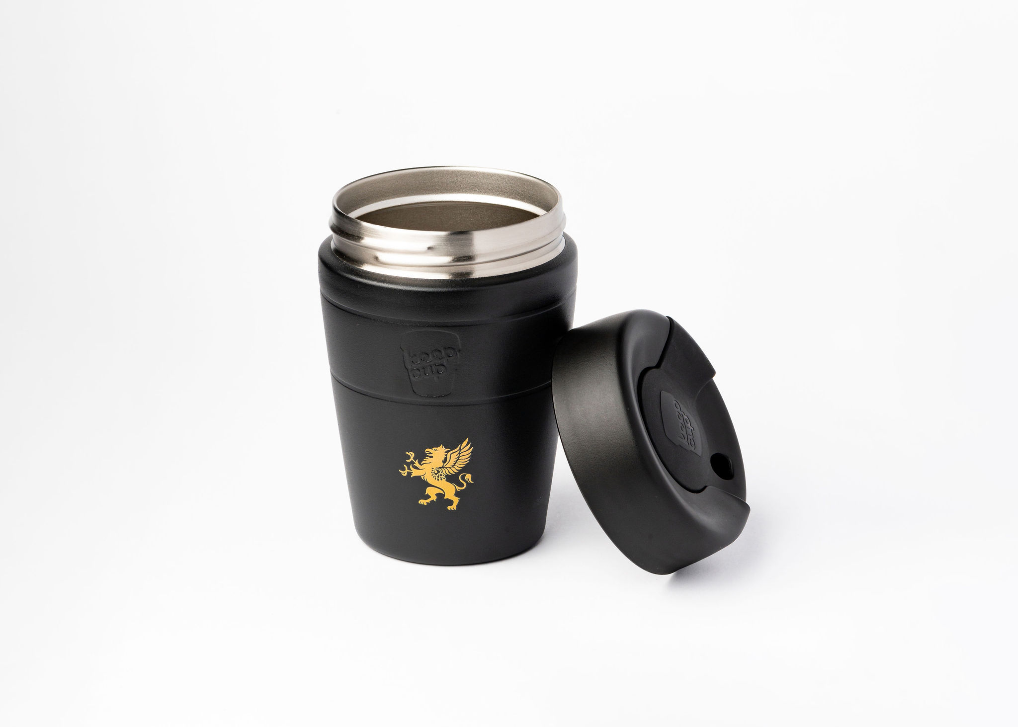 A sleek, black insulated travel mug with a metallic interior is shown against a white background. The lid is off and placed to the side, revealing the mug's opening. A gold emblem of a griffin is prominently displayed on the front of the mug. The brand name "KeepCup" is subtly embossed on the side.