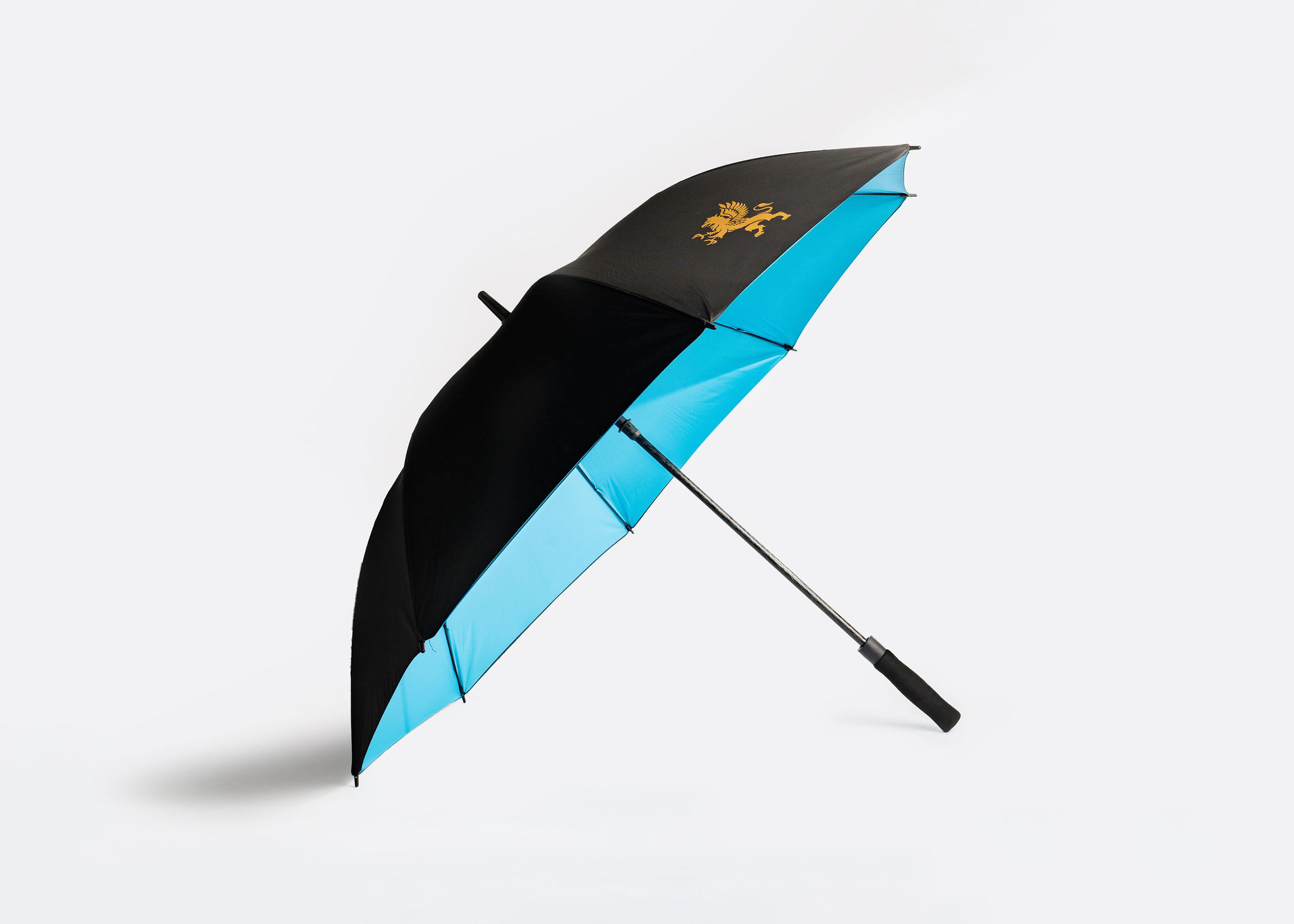 An umbrella with a black and light blue color scheme is displayed against a plain white background. The umbrella features an emblem of a golden griffin on one panel of the umbrella. The handle is sleek and black. The umbrella is positioned at an angle.