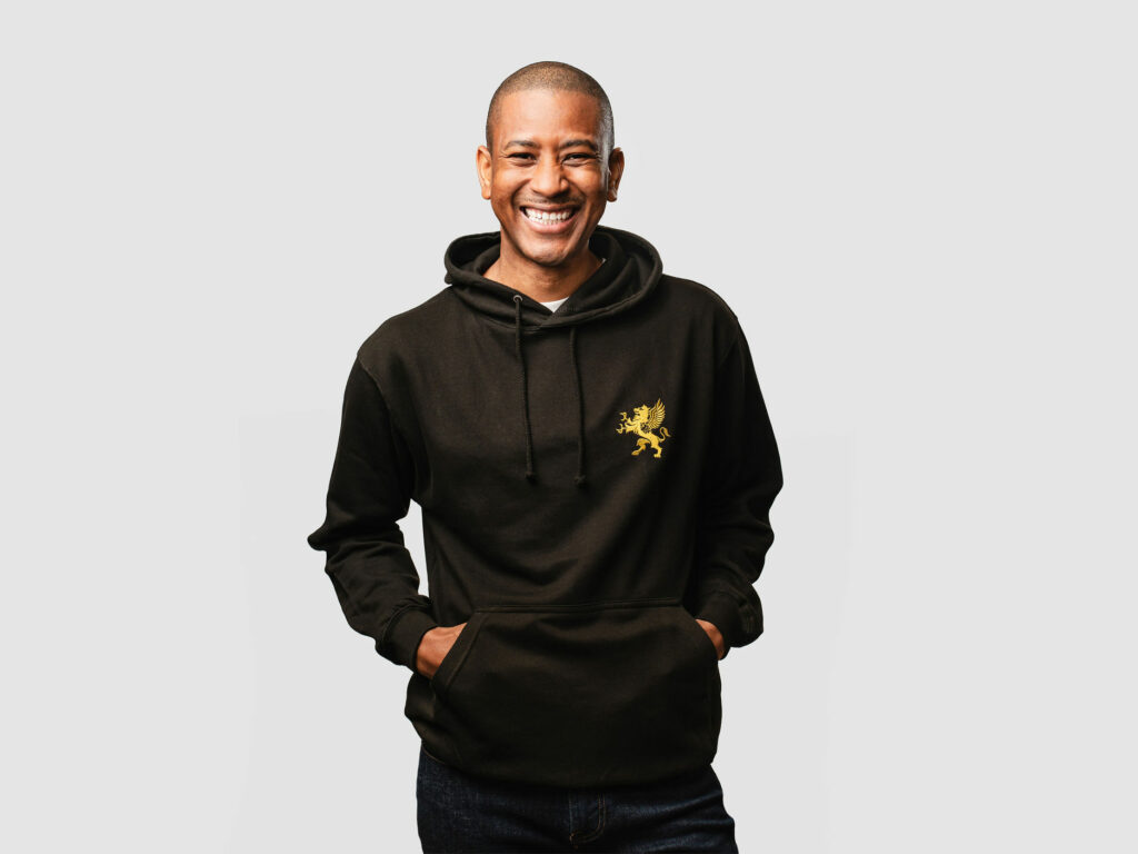 Male model wearing black hoodie with gold logo