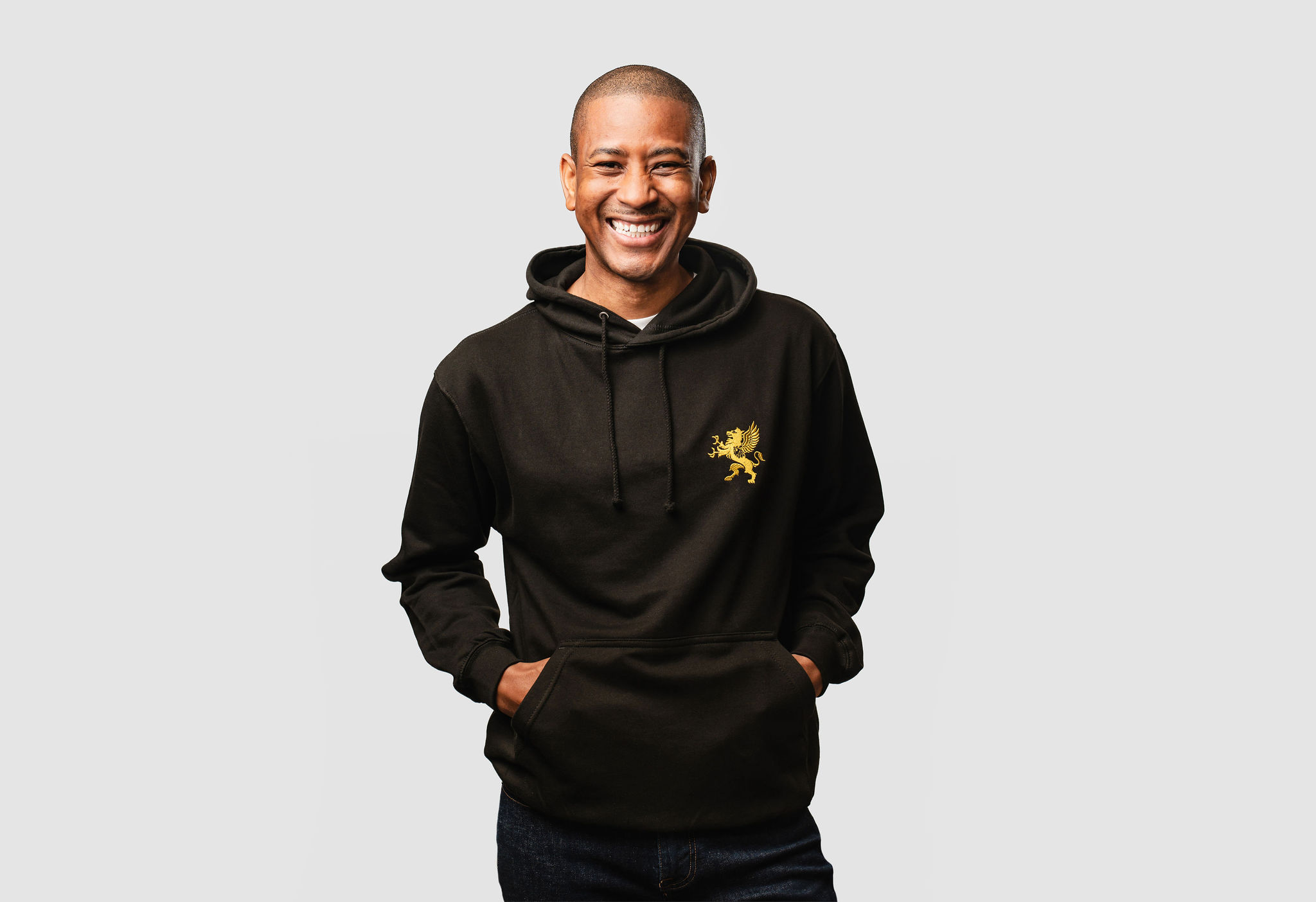 Male model wearing black hoodie with gold logo