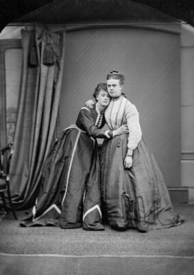 Black and white photograph of two people dressed in female clothing